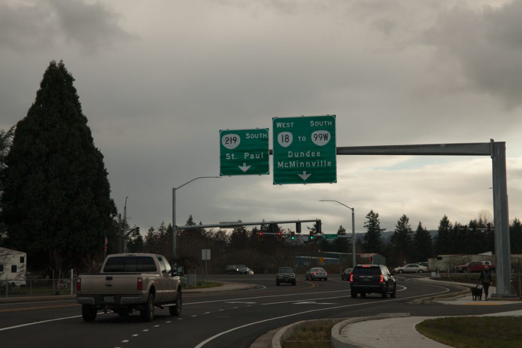 This sign shows where each left turn lane goes. From this perspective, however, it looks like the signs are pointing to the rightmost two lanes, not the leftmost. This sign also says "OR-18" instead of "TO OR-18", further implicating OR-18 traverses these roads.